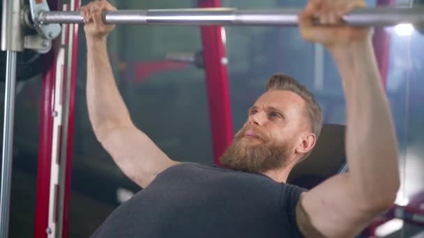 Бородатый человек в мускулистой рубашке делает упражнение пресса скамейке — стоковое видео