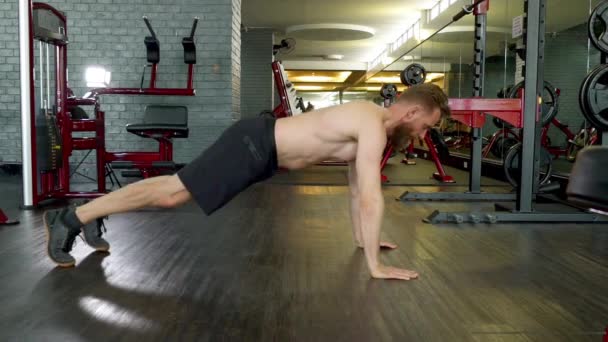 Αθλητής με τονισμένο σώμα Κάνοντας ένα άλμα Pushup σε ένα κλειστό γυμναστήριο — Αρχείο Βίντεο