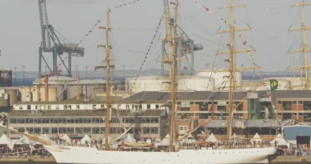 Высокий корабль Парусный корабль, пристыкованный с маленькими флагами с большой толпой людей вокруг него — стоковое видео