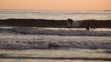 Gün batımında Yavaş Hareket Denizde Sörfçüler