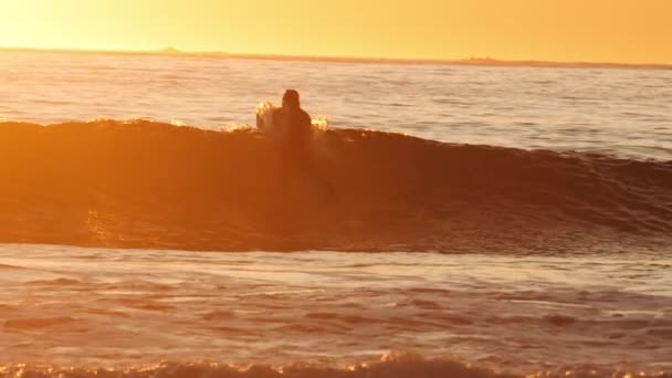 Surfer βρίσκεται επί του σκάφους στο ηλιοβασίλεμα θάλασσα — Αρχείο Βίντεο