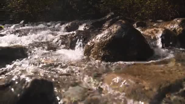 Agua que fluye sobre rocas iluminadas por el sol — Vídeo de stock