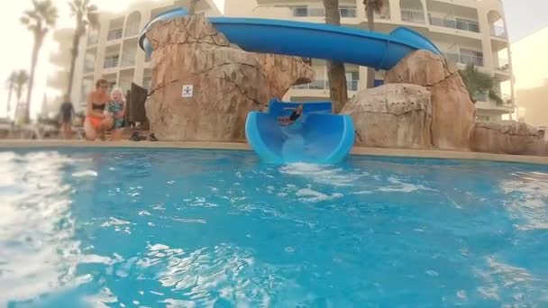 Colpo medio di una ragazza che scende lo scivolo e poi giù in piscina — Video Stock