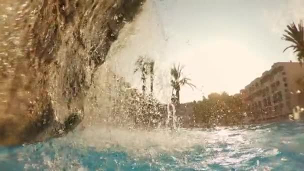 Kamera míjí padající vody odhalit pohled na resort — Stock video