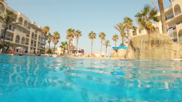 Vue d'un Resort et de la cascade artificielle depuis une caméra flottant sur la piscine — Video