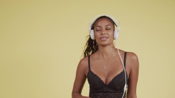 Молодая чёрная девушка в лифчике танцует в наушниках — стоковое видео