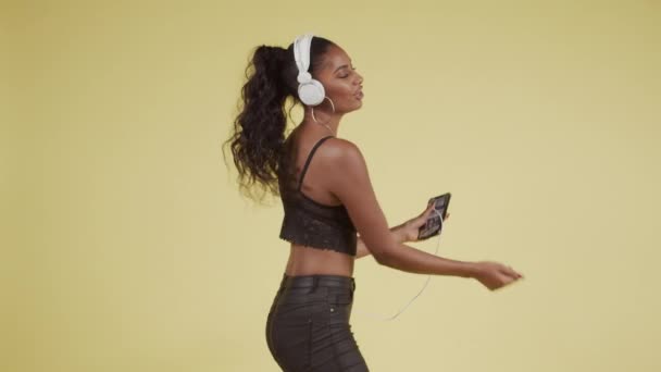 Joven chica negra bailando para teléfonos inteligentes y auriculares — Vídeo de stock