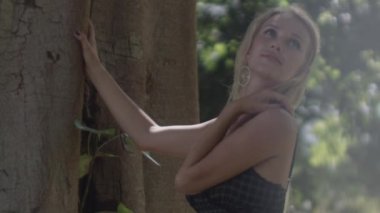 Güneş Işığı Bahçesi 'nde Ağacın yanındaki Duyarlı Sarışın Kadın