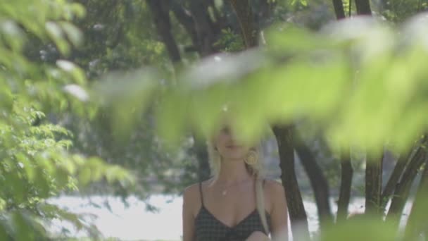 Νεαρή γυναίκα που περπατά ανάμεσα στα φυτά και απολαμβάνει τον ηλιόλουστο κήπο — Αρχείο Βίντεο