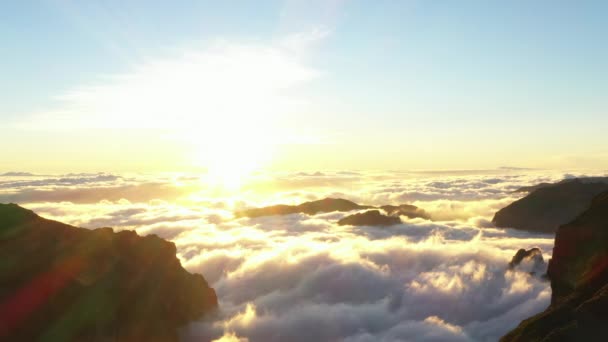 Brillante puesta de sol sobre nubes que cubren la cima de la montaña — Vídeos de Stock