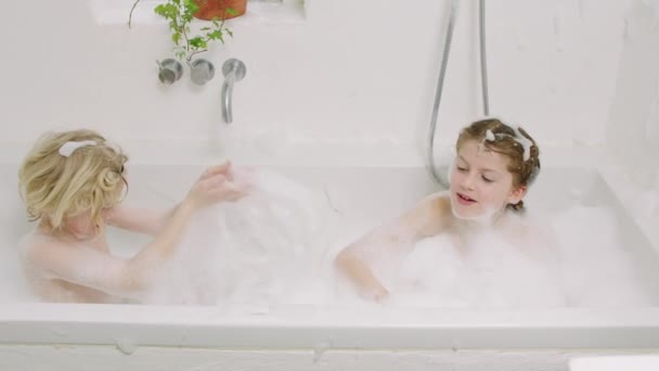 Kinder spritzen Wasser und Seife aus Badewanne — Stockvideo