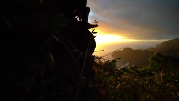 Man sitter på berget sida och tittar på solen stiga — Stockvideo