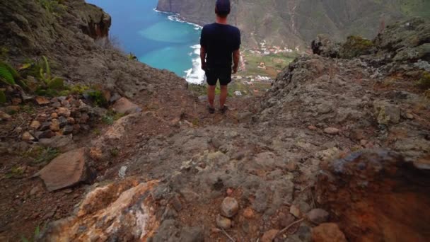 Hombre en la montaña mirando la costa y el mar — Vídeo de stock