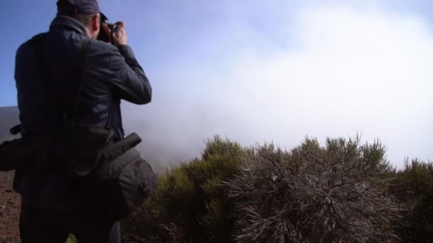 Fotograf steht und fotografiert wolkenverhangene Landschaft — Stockvideo