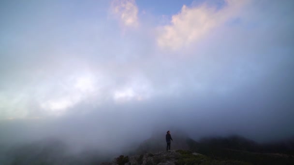 Μοναχικός άντρας στέκεται στην άκρη του βράχου βλέποντας ομίχλη — Αρχείο Βίντεο
