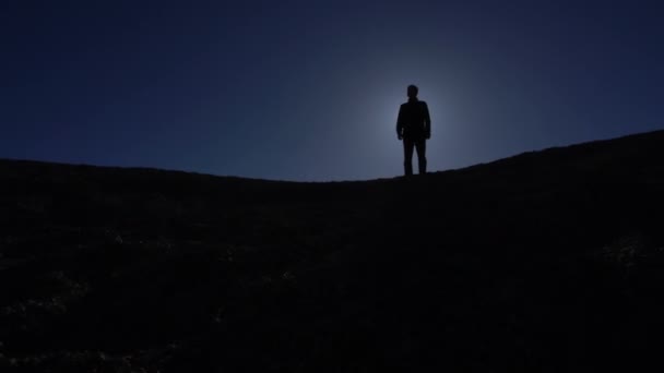 Hombre de pie en silueta retroiluminado por sol brillante — Vídeo de stock