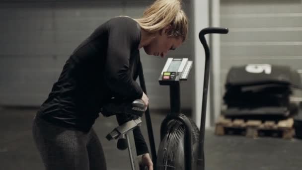 Atleta feminina ajustando bicicleta de treinamento cruzado — Vídeo de Stock