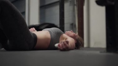 Spor salonunda yatan bitkin düşmüş bayan sporcu.