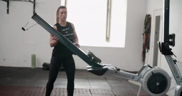 Atleta femenina que organiza la máquina de remo en el gimnasio — Vídeos de Stock