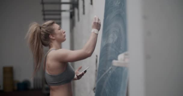 Female Athlete Using Smartphone And Writing In Chalk — Stock Video