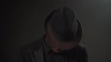 Siyah takım elbiseli ve şapkalı adam dans edip şarkı söylüyor.