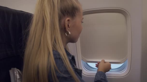 Adolescent fille levage aveugle sur avion fenêtre — Video