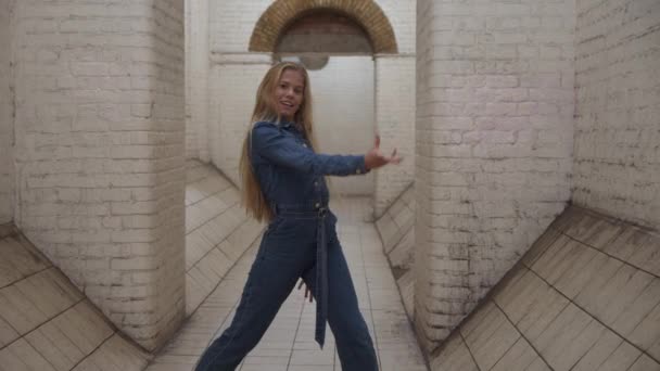 Блондинка в комбинезоне танцует в тоннеле — стоковое видео
