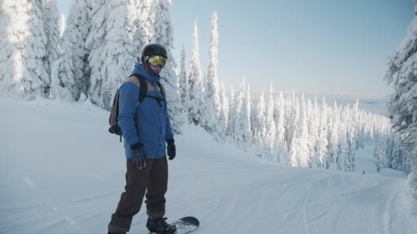 Snowboarder gesticolando per la fotocamera prima di muoversi in discesa — Video Stock
