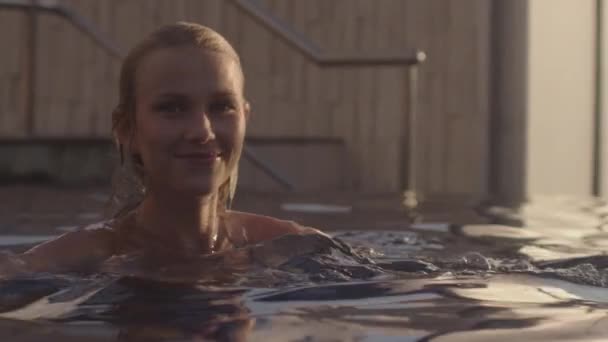 Mulher bonita nadando na piscina do hotel iluminado pelo sol — Vídeo de Stock
