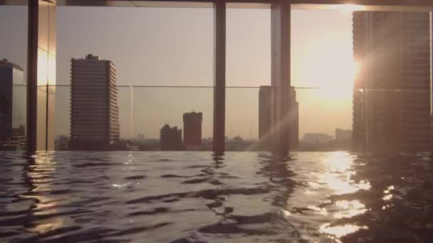 Sol brillando a través de rascacielos en la piscina infinita — Vídeo de stock