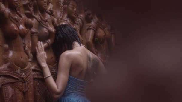Женщина в синем платье, ласкающая статуи храма — стоковое видео