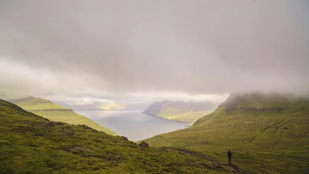 Muž stojící pod mraky pohybující se nad fjordem — Stock video