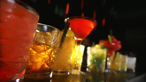 Bebidas de cóctel alineadas en una mesa de bar durante una fiesta nocturna — Vídeo de stock