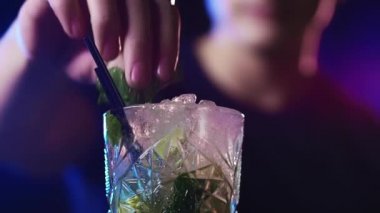 Erkek Barmen Nane Yapraklarını Kokteyllere Koyuyor ve Kollarını Esnetiyor