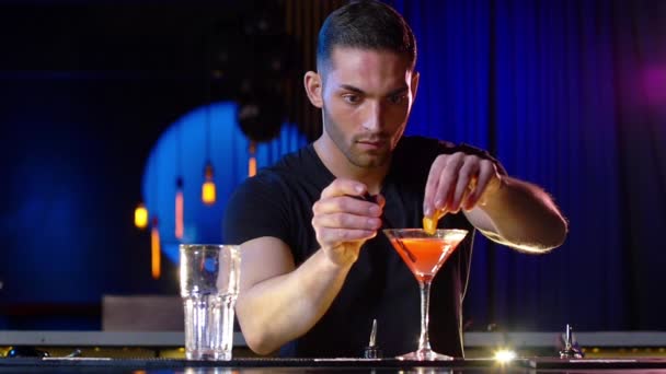 Knappe mannelijke barman zetten op stro op een cocktail dan glimlacht — Stockvideo