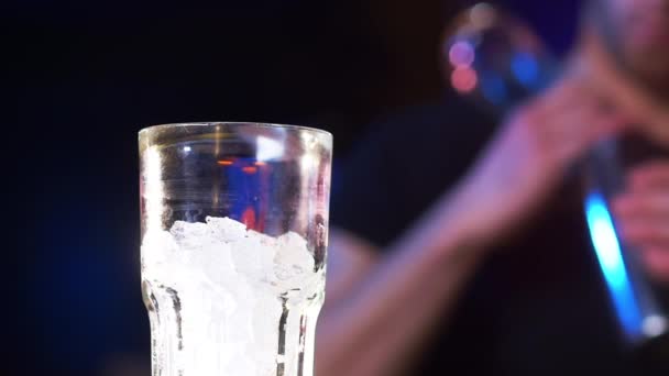 Gros plan d'un verre avec glace comme mâle barman verse cocktail — Video