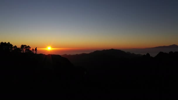 Człowiek w sylwetce ogląda zachód słońca nad górami — Wideo stockowe
