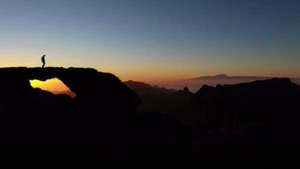 Silhouette eines Mannes auf Felsen beim Sonnenuntergang — Stockvideo