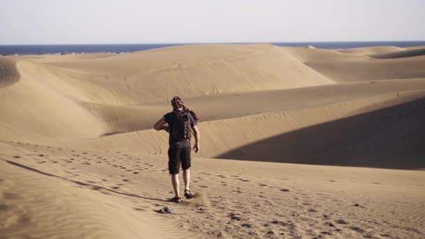Hombre caminando en dunas de arena — Vídeos de Stock