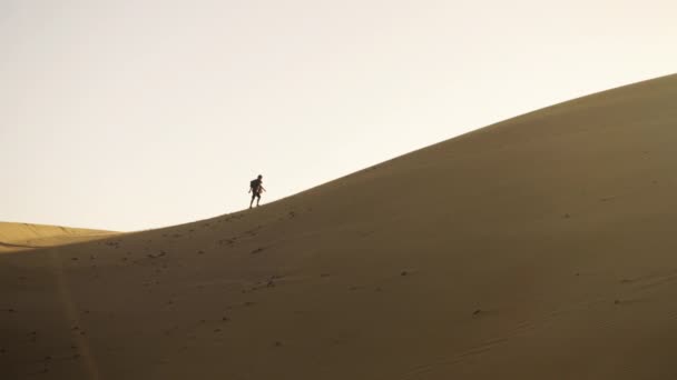 Homme montant la dune de sable dans le désert 