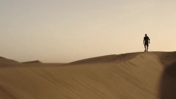 Homme marchant le long de la dune de sable dans le désert — Video