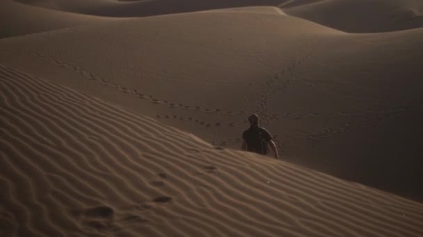Homem caminhando para baixo areia duna no deserto — Vídeo de Stock