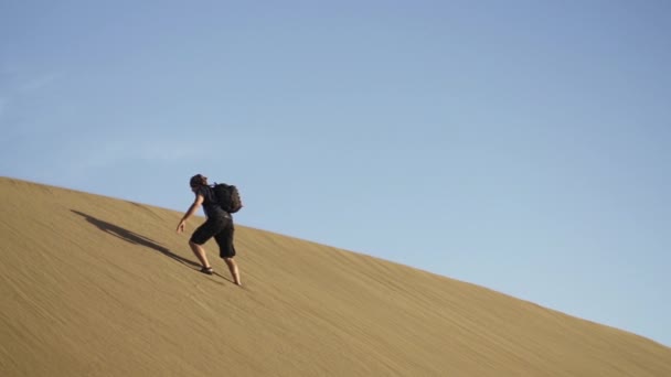 Man går till toppen av brant sand sanddyn — Stockvideo