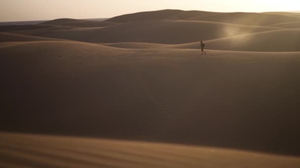 Homem caminhando ao longo de dunas de areia — Vídeo de Stock