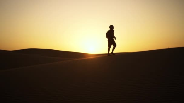 Silueta del hombre caminando a lo largo de las dunas de arena — Vídeo de stock