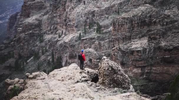 Hombre al borde de acantilado mirando la montaña — Vídeo de stock