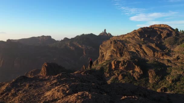 Man på klippor ser ut över berg — Stockvideo