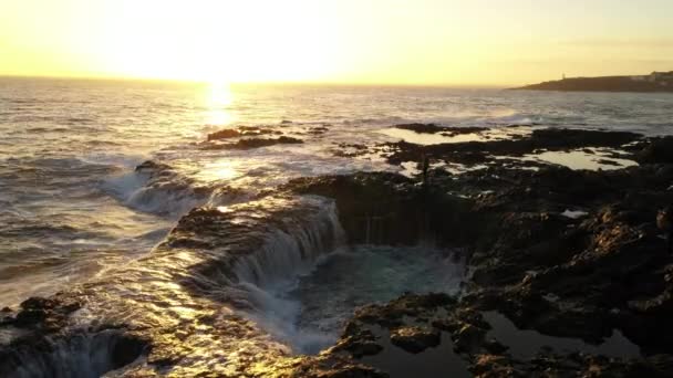 Человек наблюдает, как море заливает бассейны с камнями на закате — стоковое видео