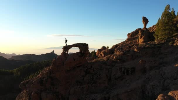 Homme sur l'arc de roche regardant les montagnes — Video