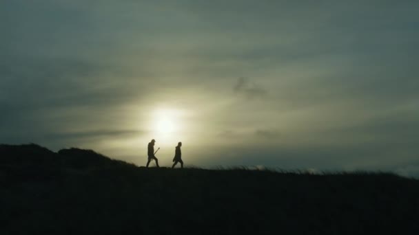 Silueta de hombres caminando contra la puesta de sol — Vídeo de stock